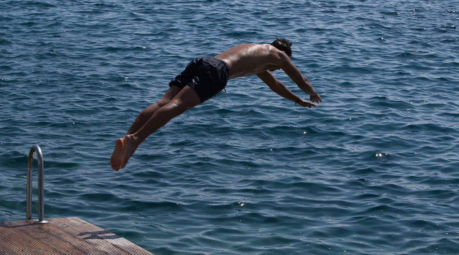 Male Model diving into clear blue Mediterranean waters